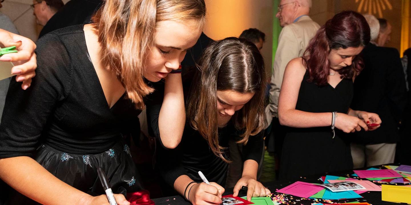 Girls writing on photos at a party table_PC_Drew Altizer Photography.