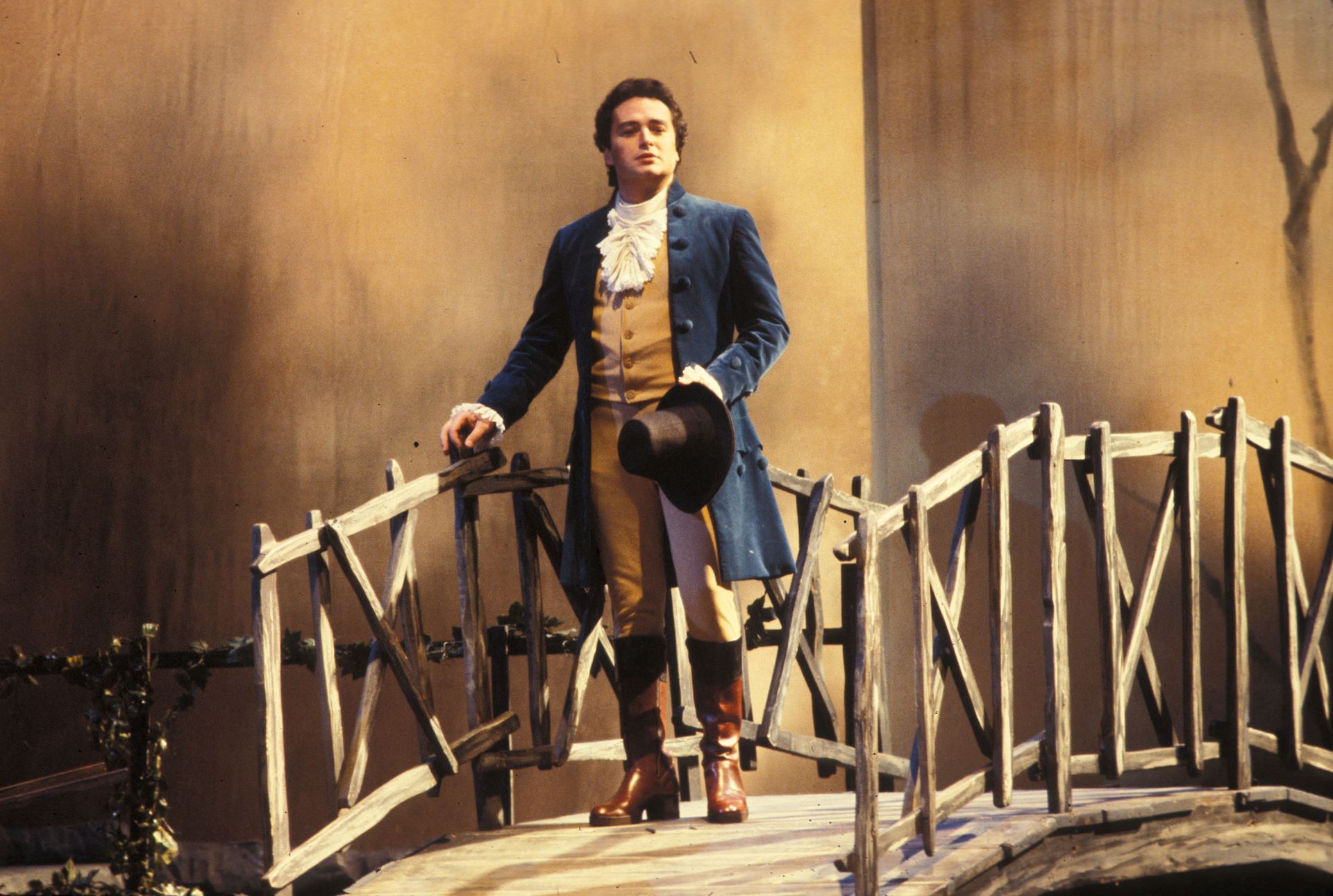 Scene from 1978 WERTHER - A man is standing on a bridge holding a hat
