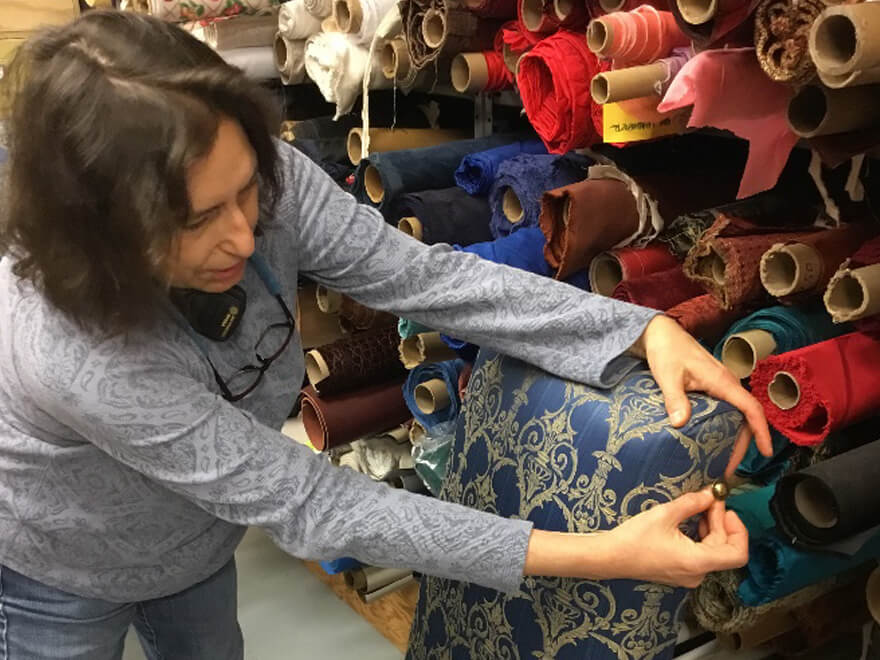 SFO-upholstered chairs in the fabric/upholstery room in the fly tower and Properties Master Lori Harrison testing out the upholstery nails.