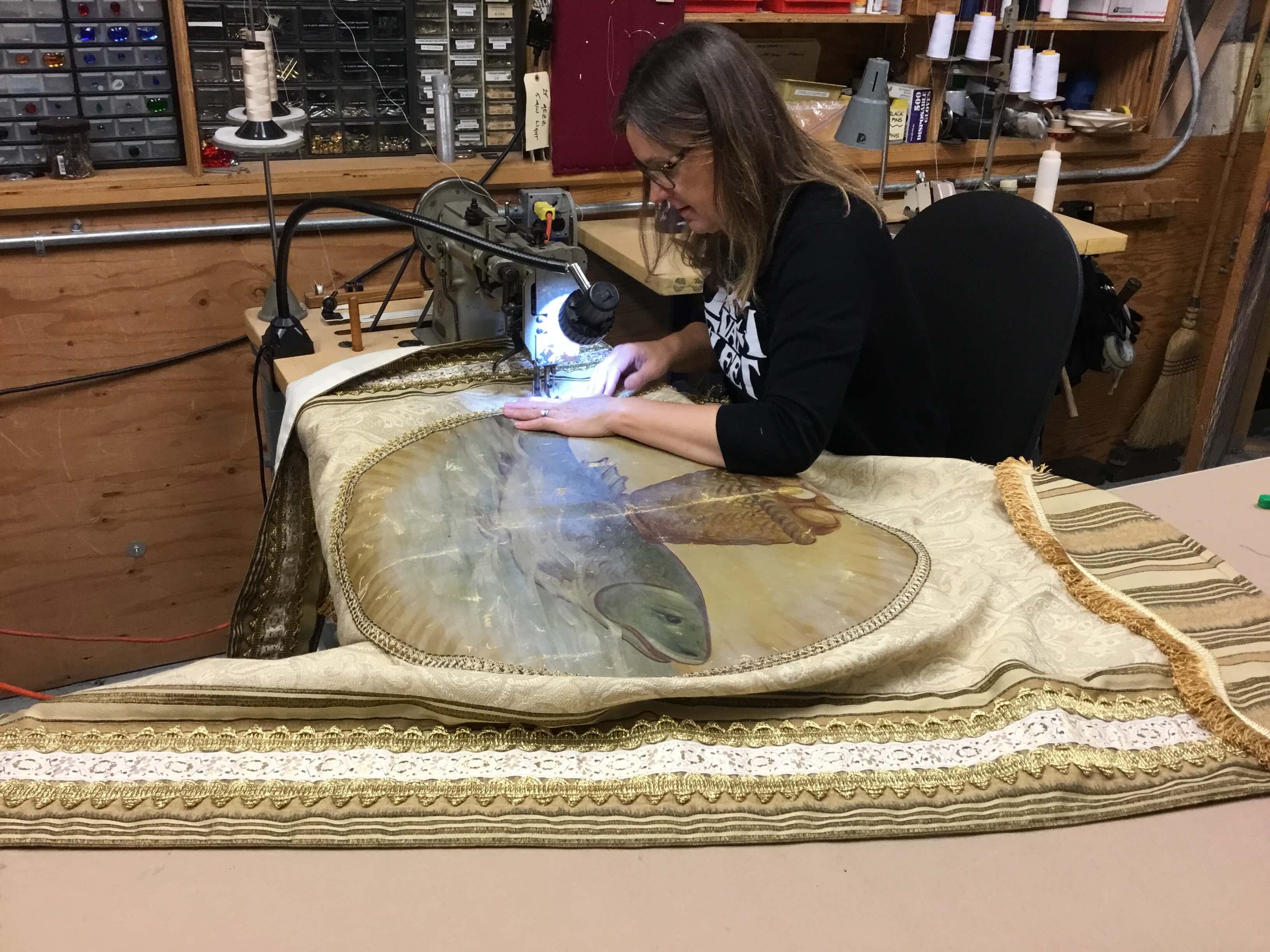 Tara Pellack stitching one of the banners for Act I of Tosca using an actual church painting at the center and banner research.
