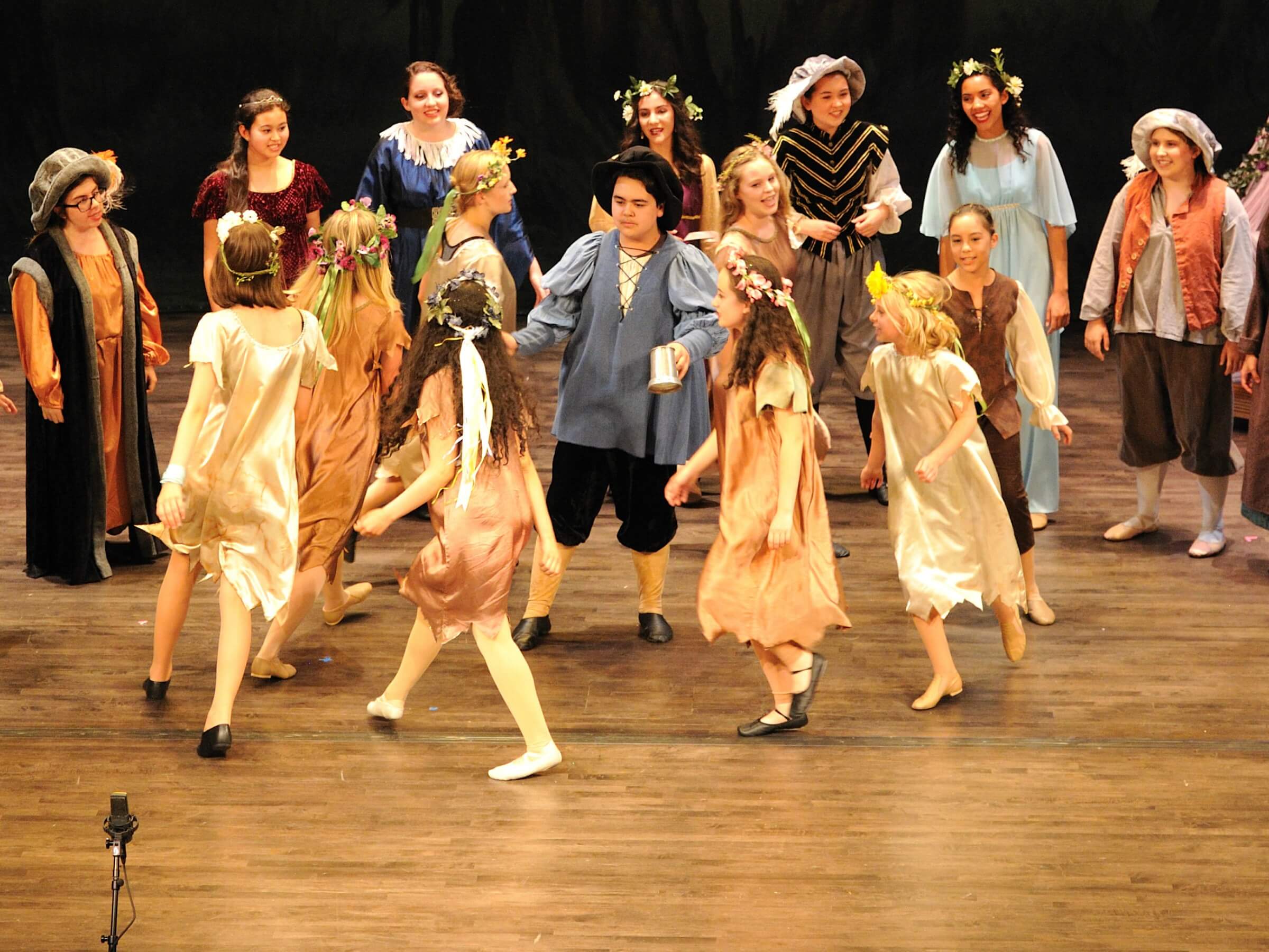 Students performing in costumes dancing in a circle