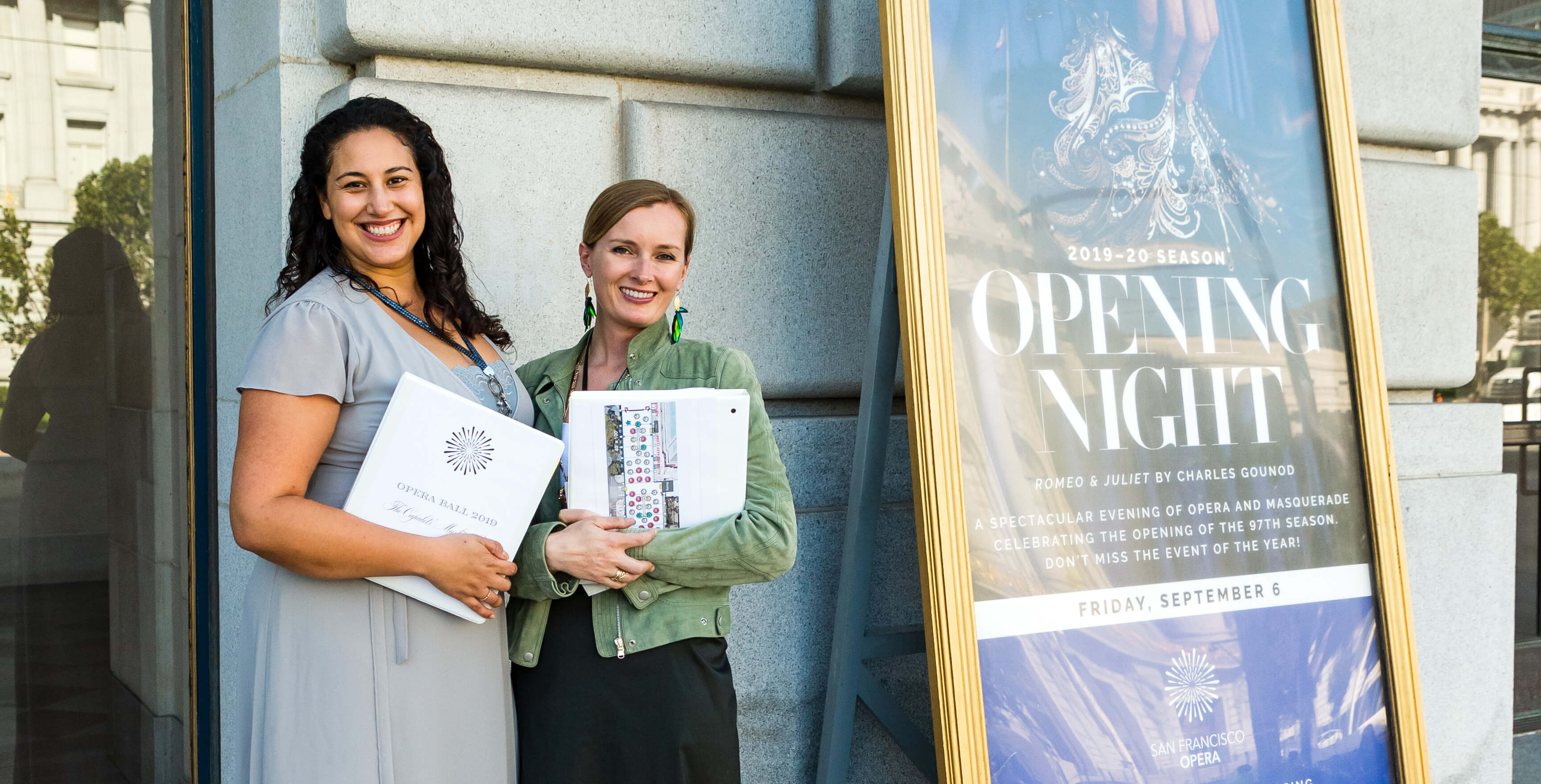 Opera volunteers next to Opening Night sign
