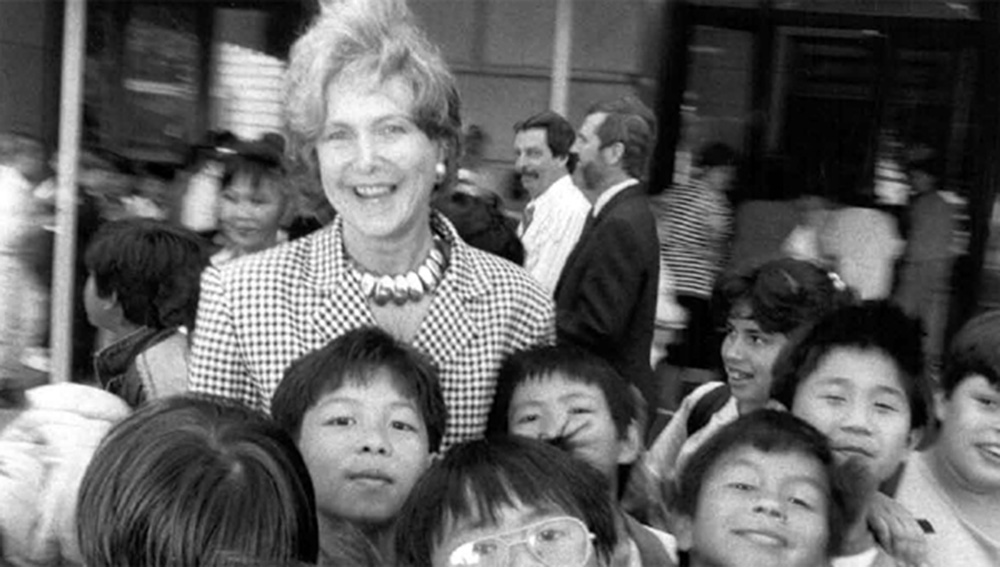 Black and white photo of a woman standing with a group of children