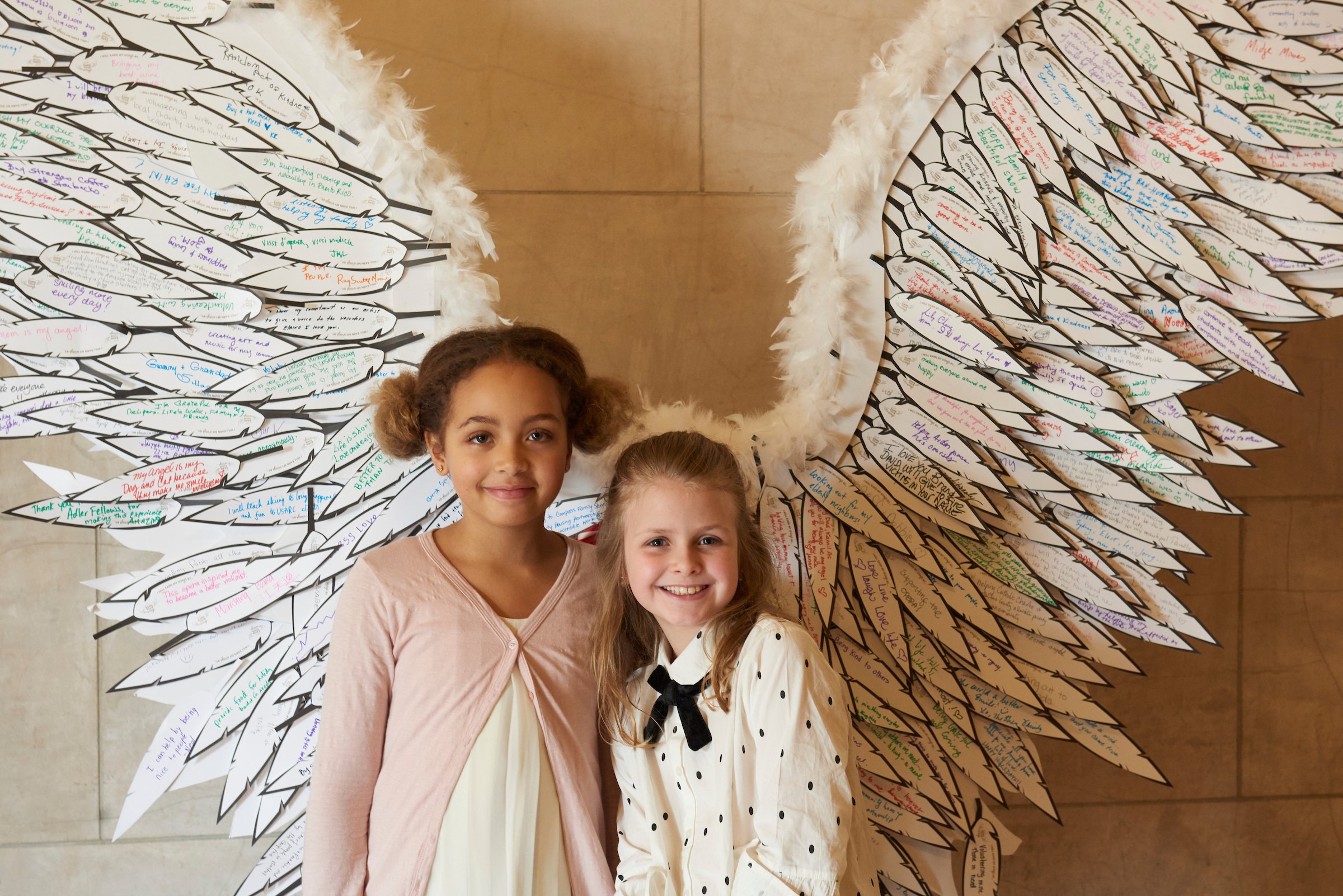 Two children standing in front of paper wings