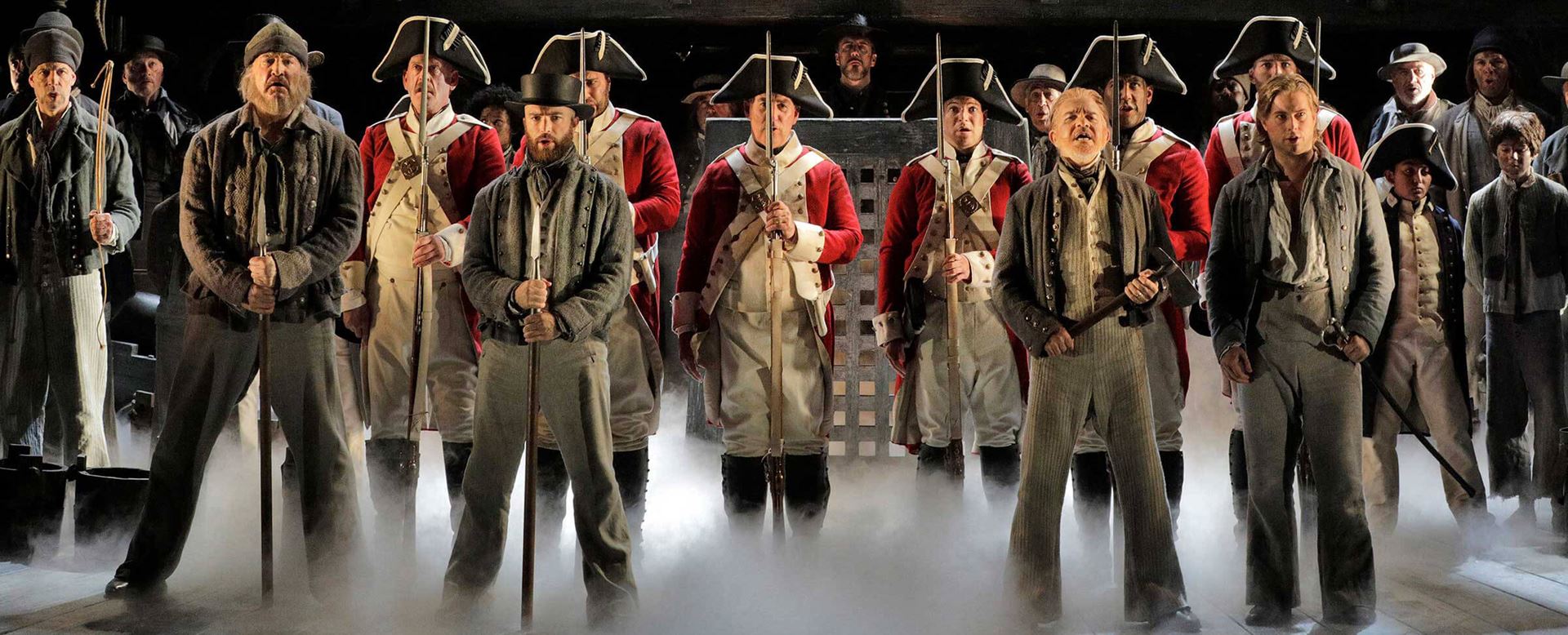 Billy Budd Opera cast in military uniforms standing at attention as header image for operas meaning.