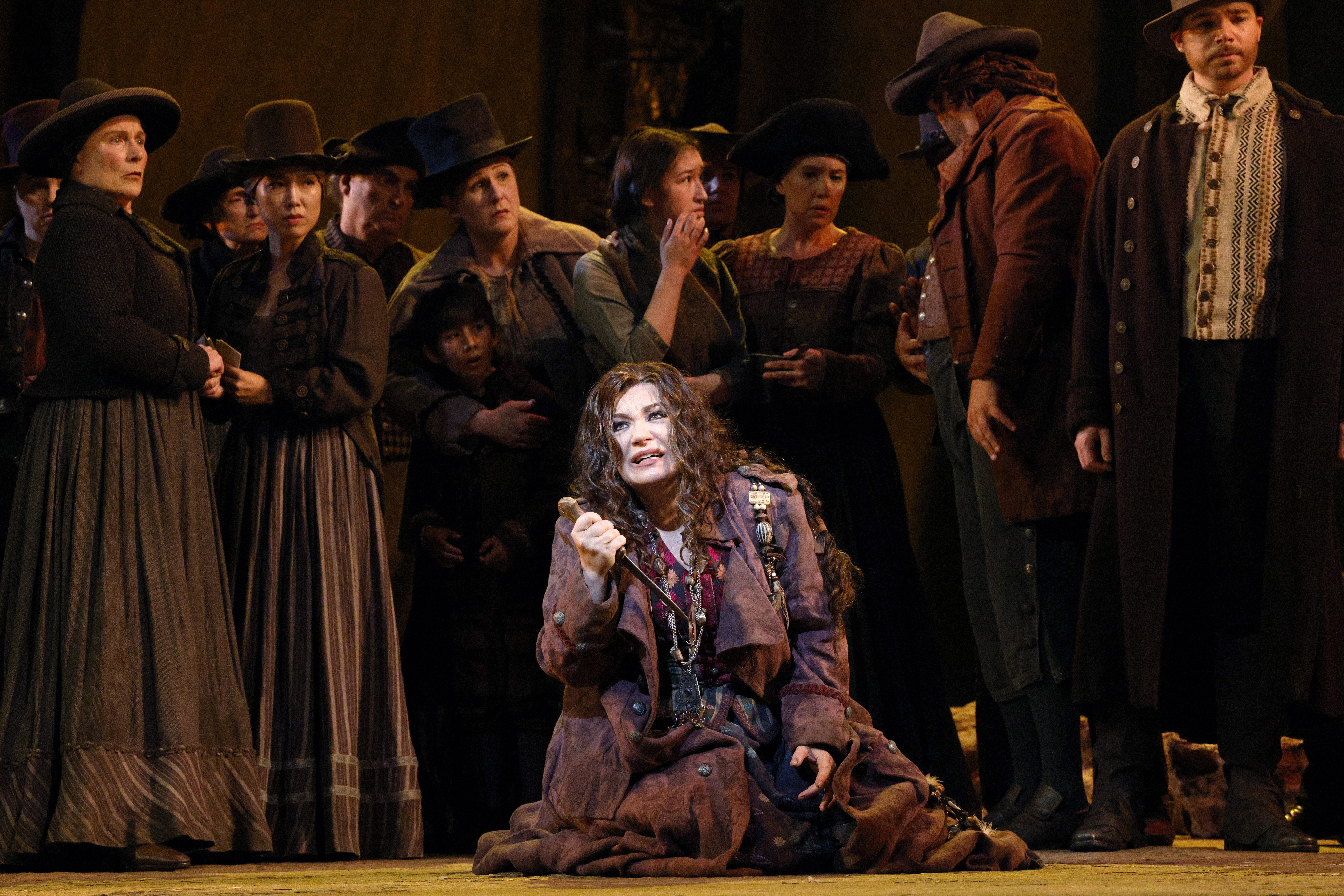 women on stage in front of townsfolk singing