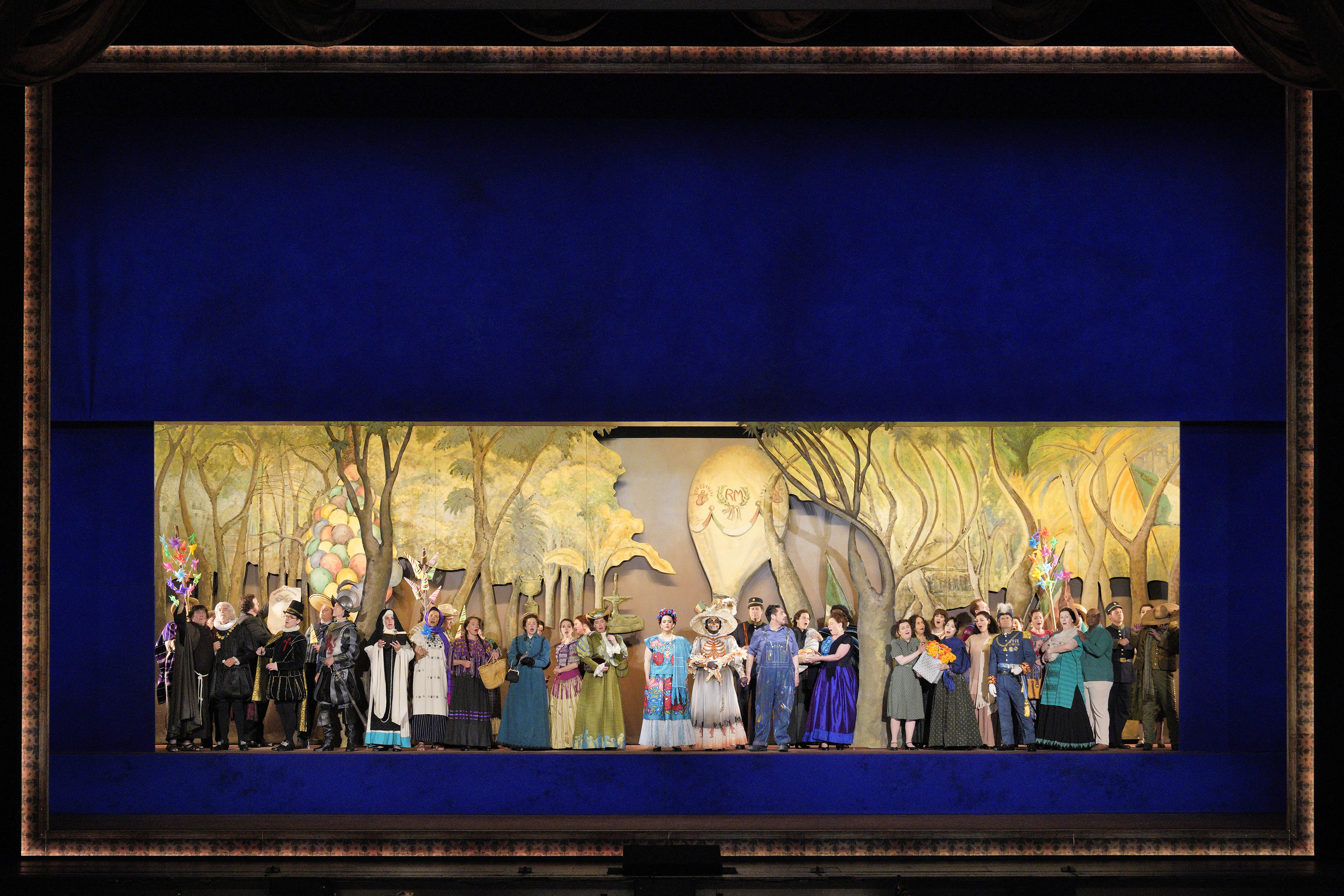 Scene from Frida A group of people standing on stage in front of a painting of a forest