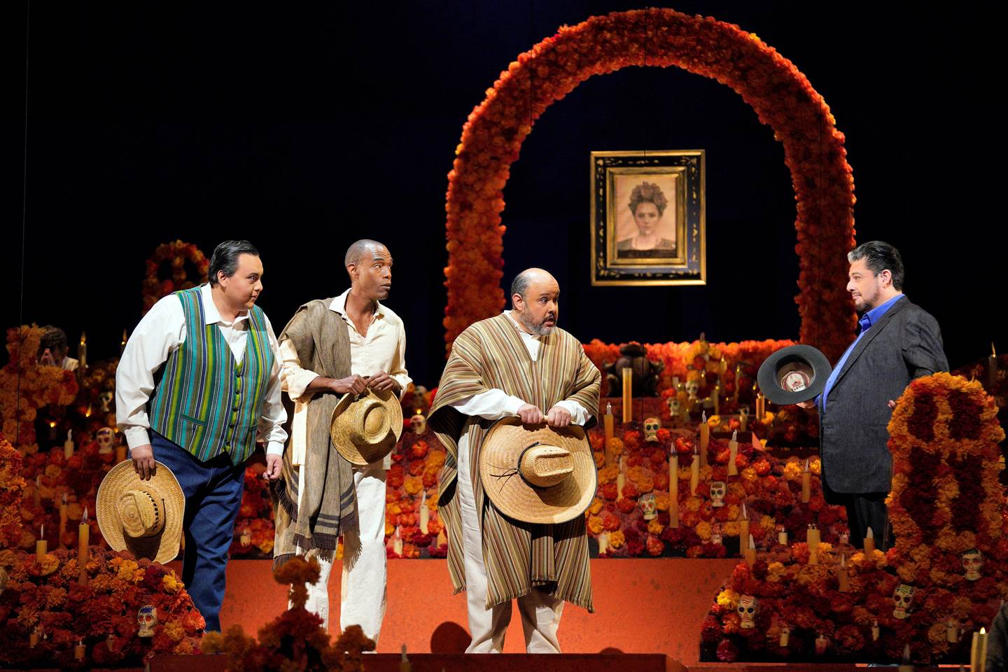 Scene from Frida with three men with their hats off talking to a man in a black suit