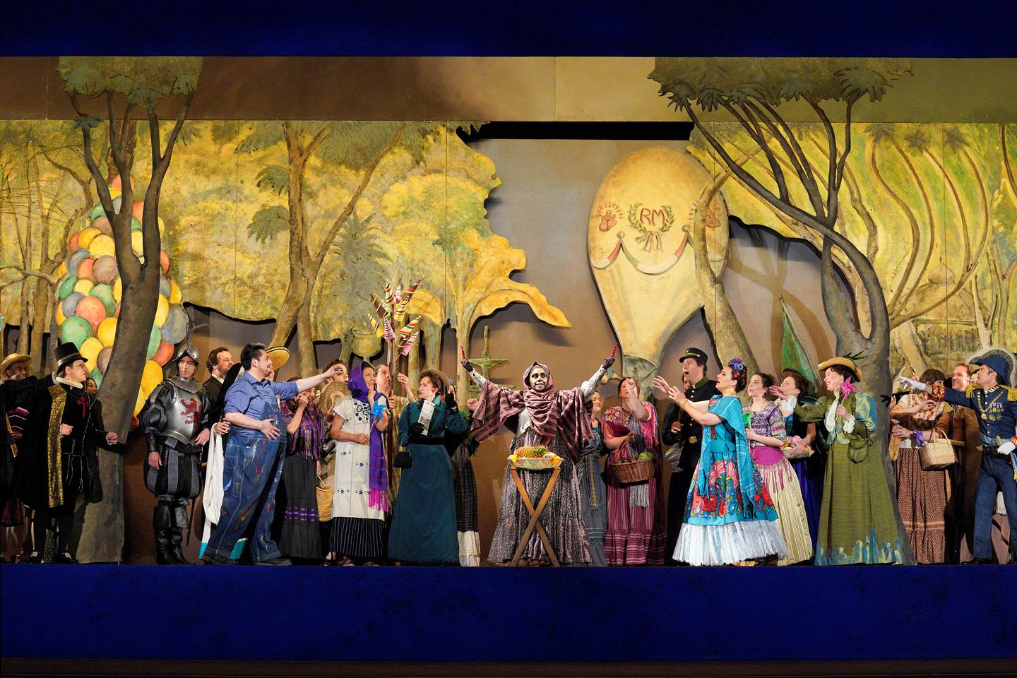 Scene from Frida A group of people standing on stage in front of a painting of forest with a person in skeleton costume at the center