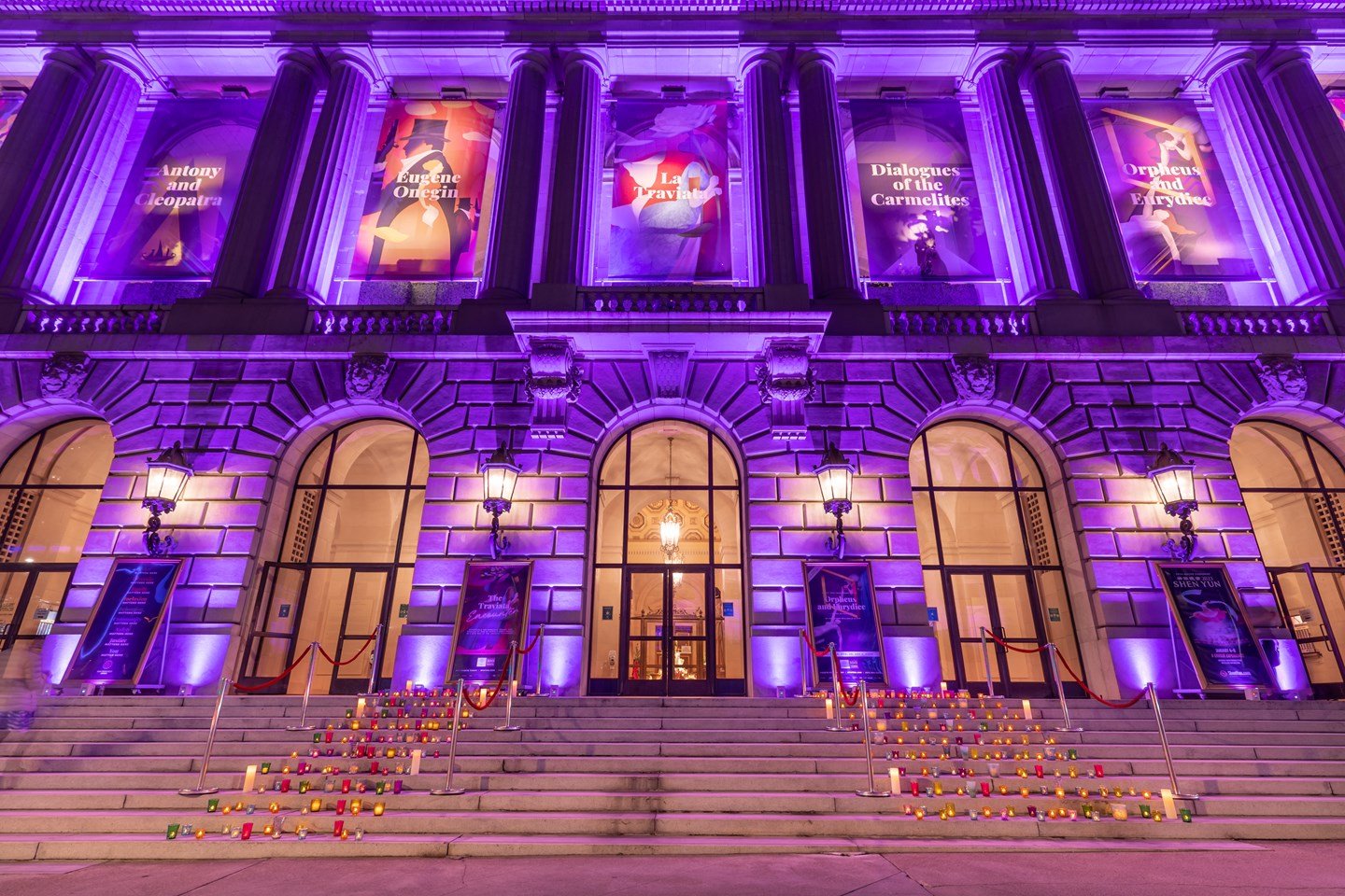 War Memorial Opera House lit up in purple with candles on the steps