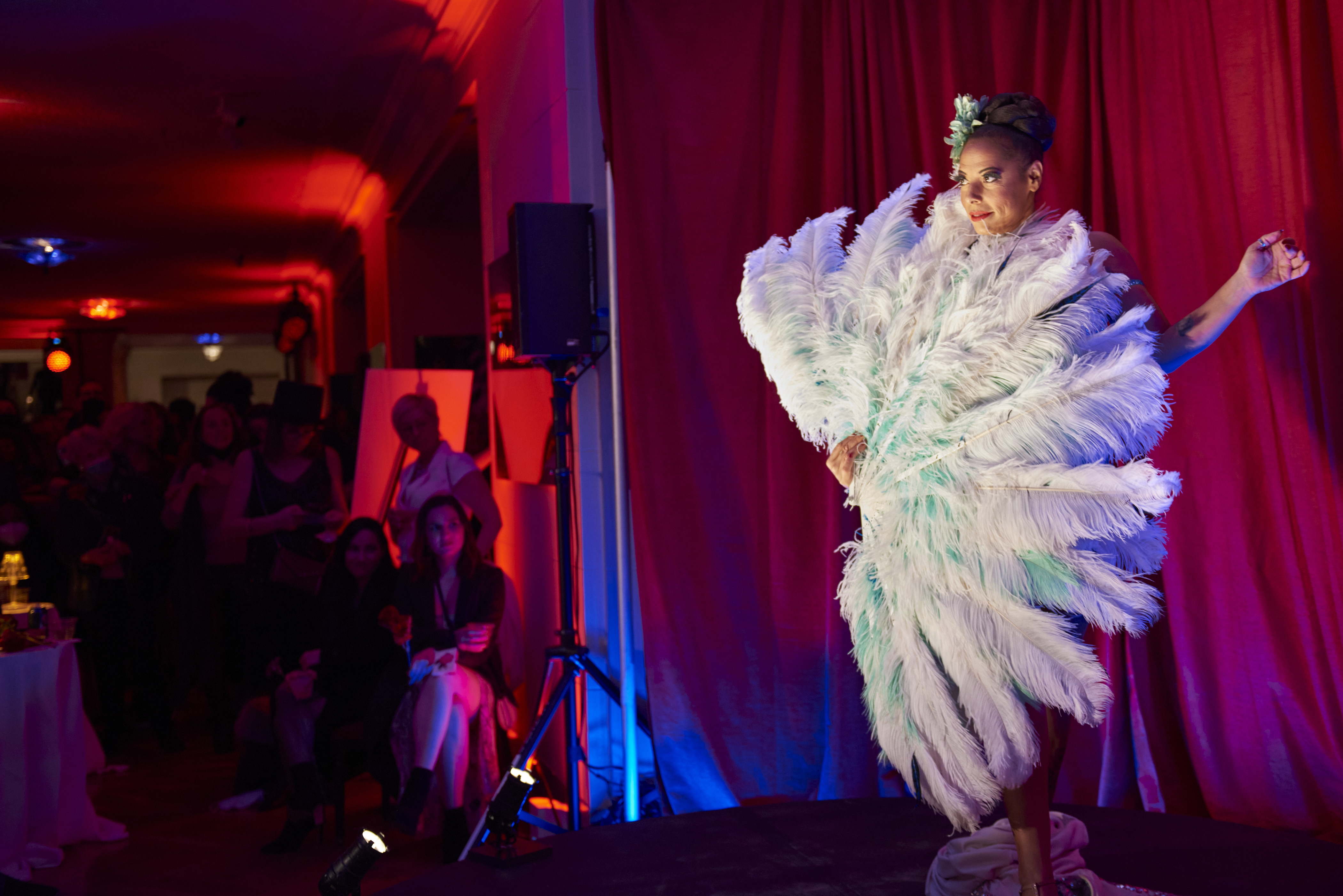 performer on stage with a large feather fan covering their body