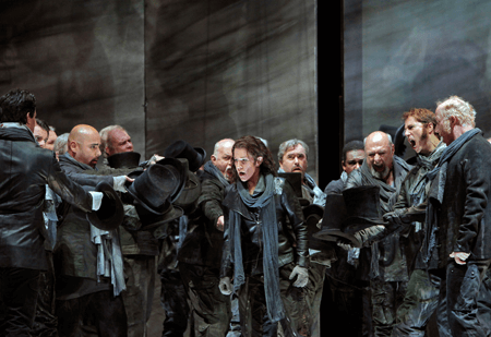 opera characters shouting at a man while holding their top hats out.