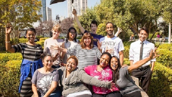 A group of people standing in a park smiling and posing for the camera