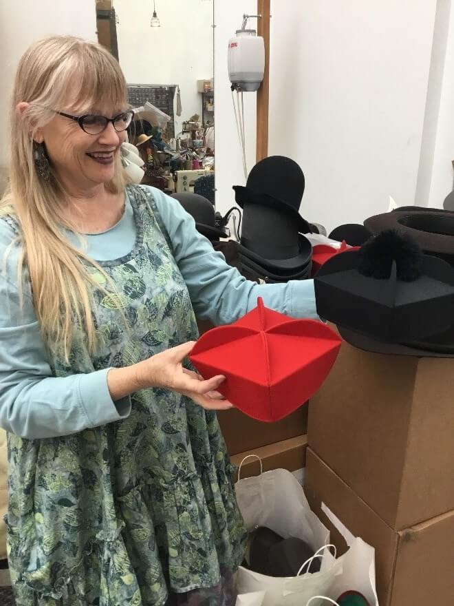 Senior Milliner, Paula Wheeler, with a red priest hat that she has made for Tosca.