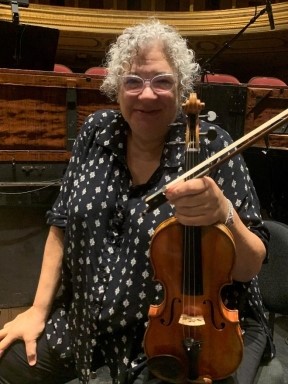 Kay Stern sitting on a chair supporting her violin and bow