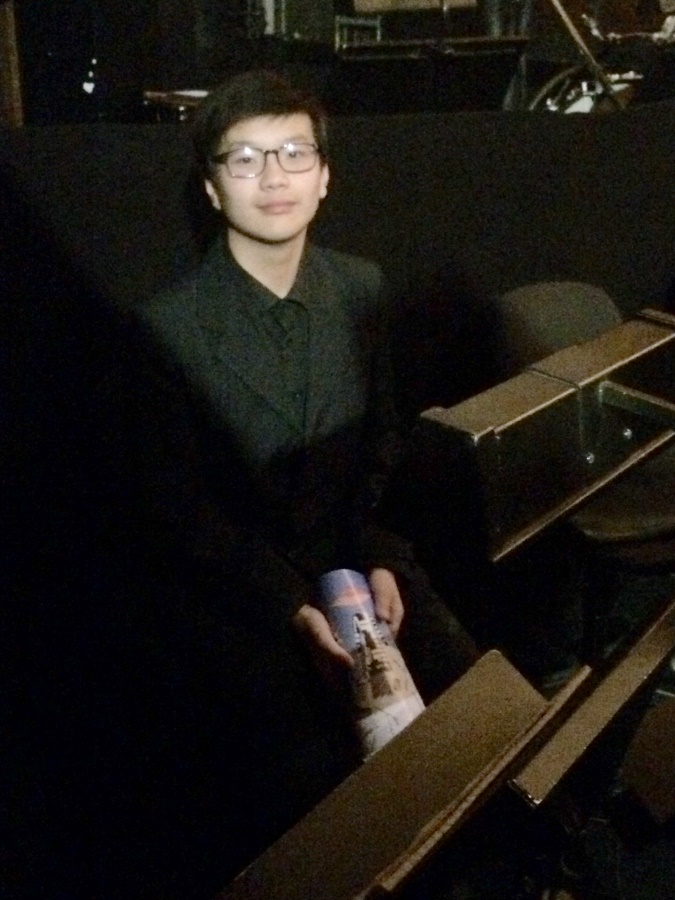 Trumpet student Shanzhi Yu sitting in the principal trumpet’s chair in the Opera House pit. 