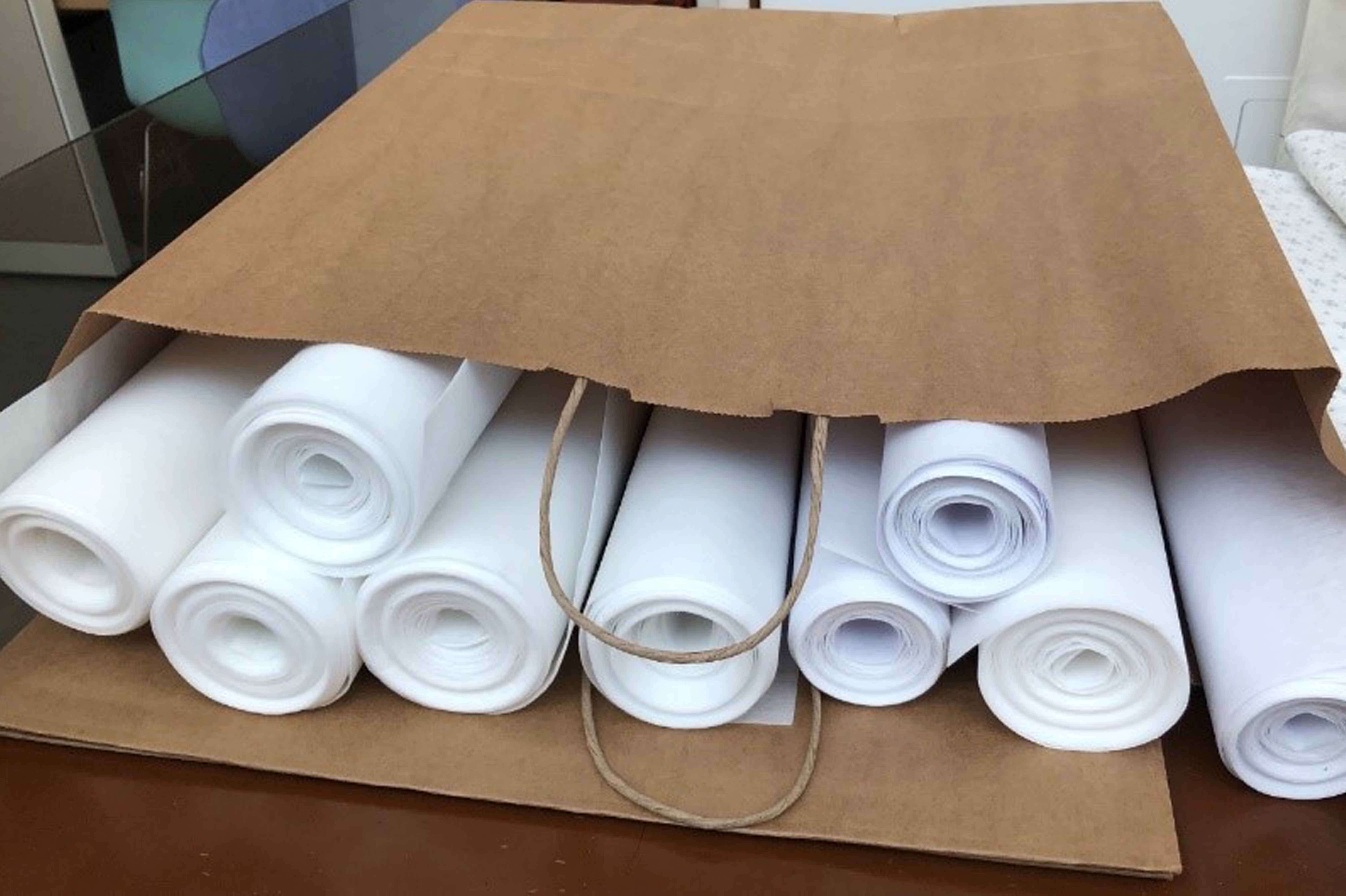Pellon 50 interfacing, rolled, and prepared to be included in the packets that are being sent out to stitchers. 