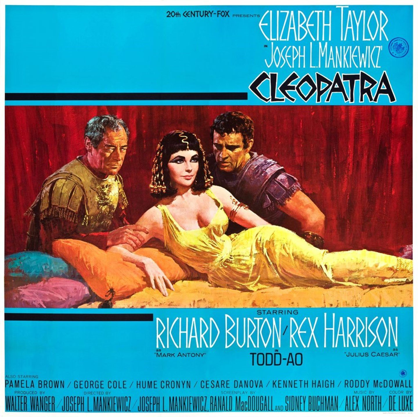 Elizabeth Taylor as Cleopatra poses laying down with two men staring at her