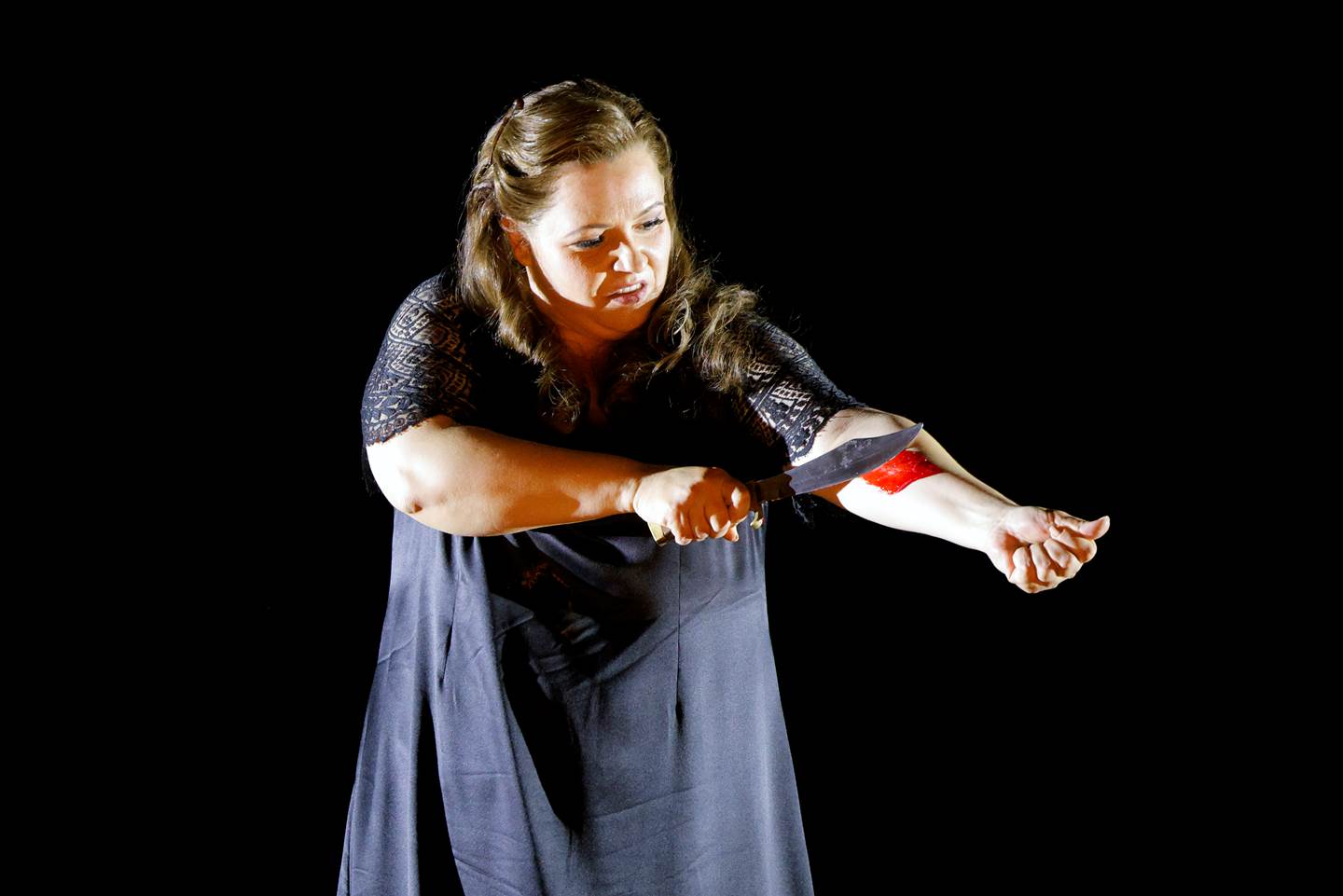 women apparently cutting her arm with a large knife