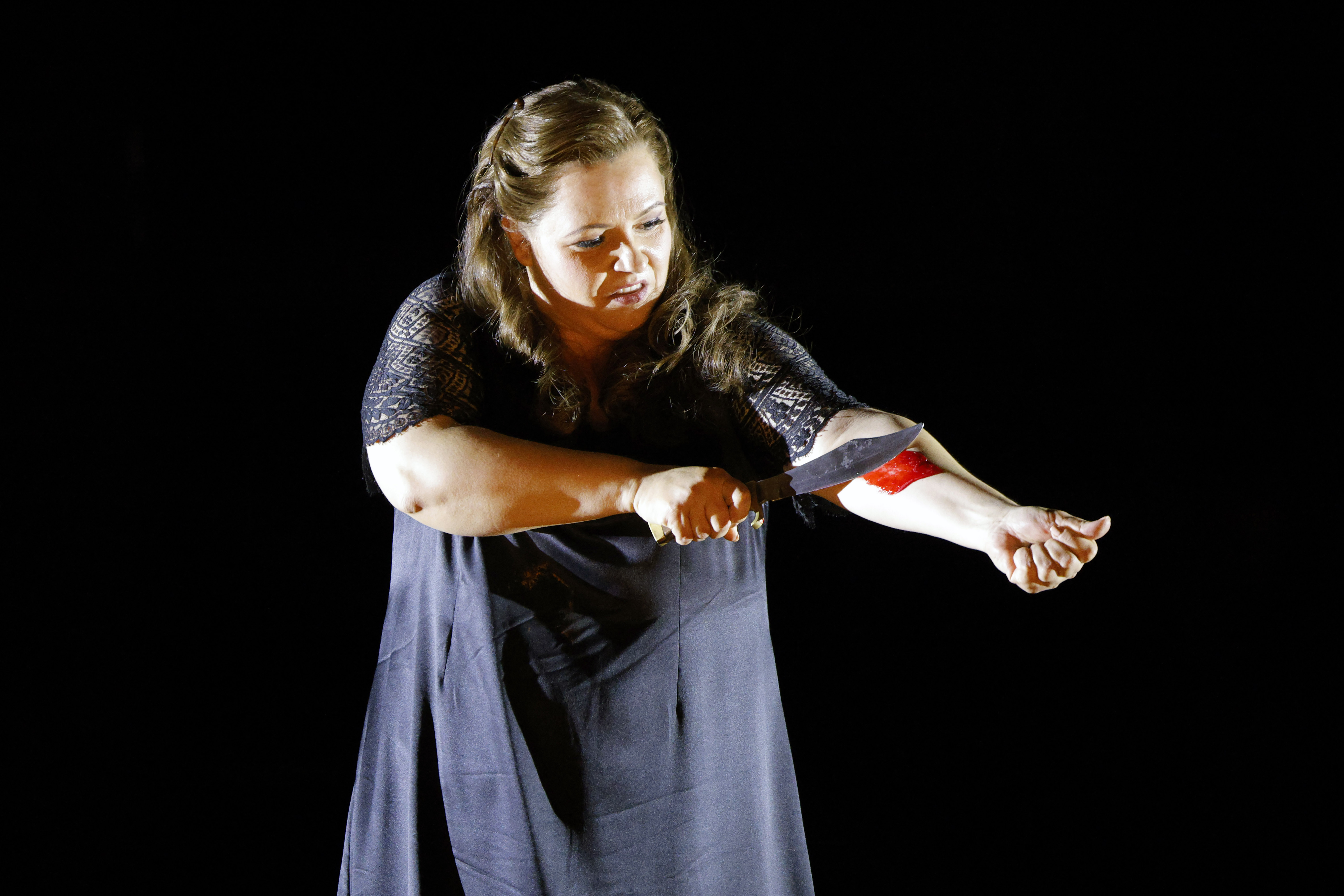 women apparently cutting her arm with a large knife