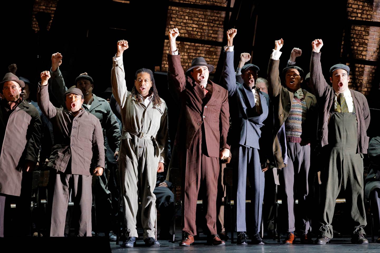 men on stage with right arms extended