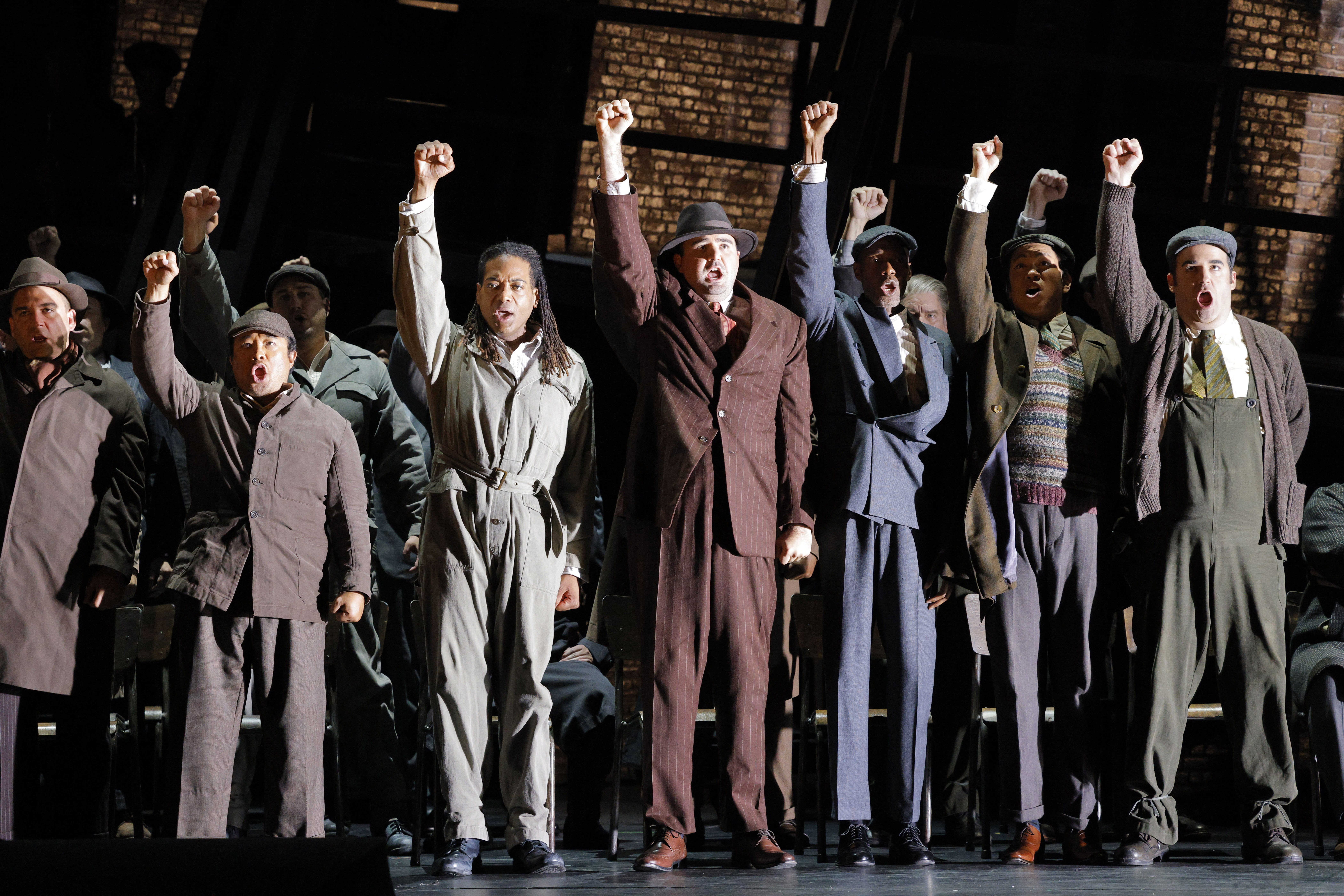 men on stage with right arms extended