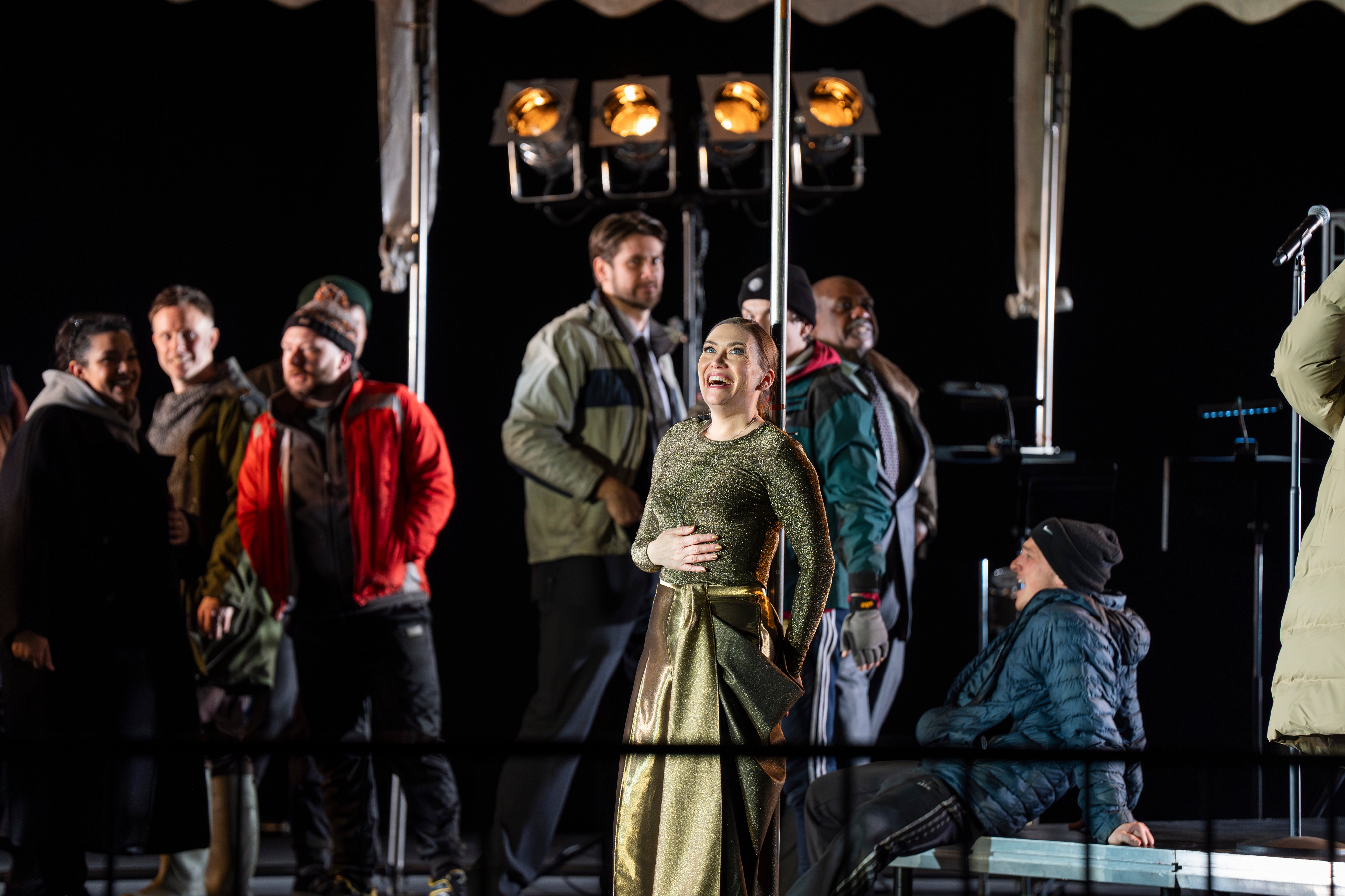 Heidi Stober in a gold dress, surrounded by the chorus in Mary, Queen of Scots.