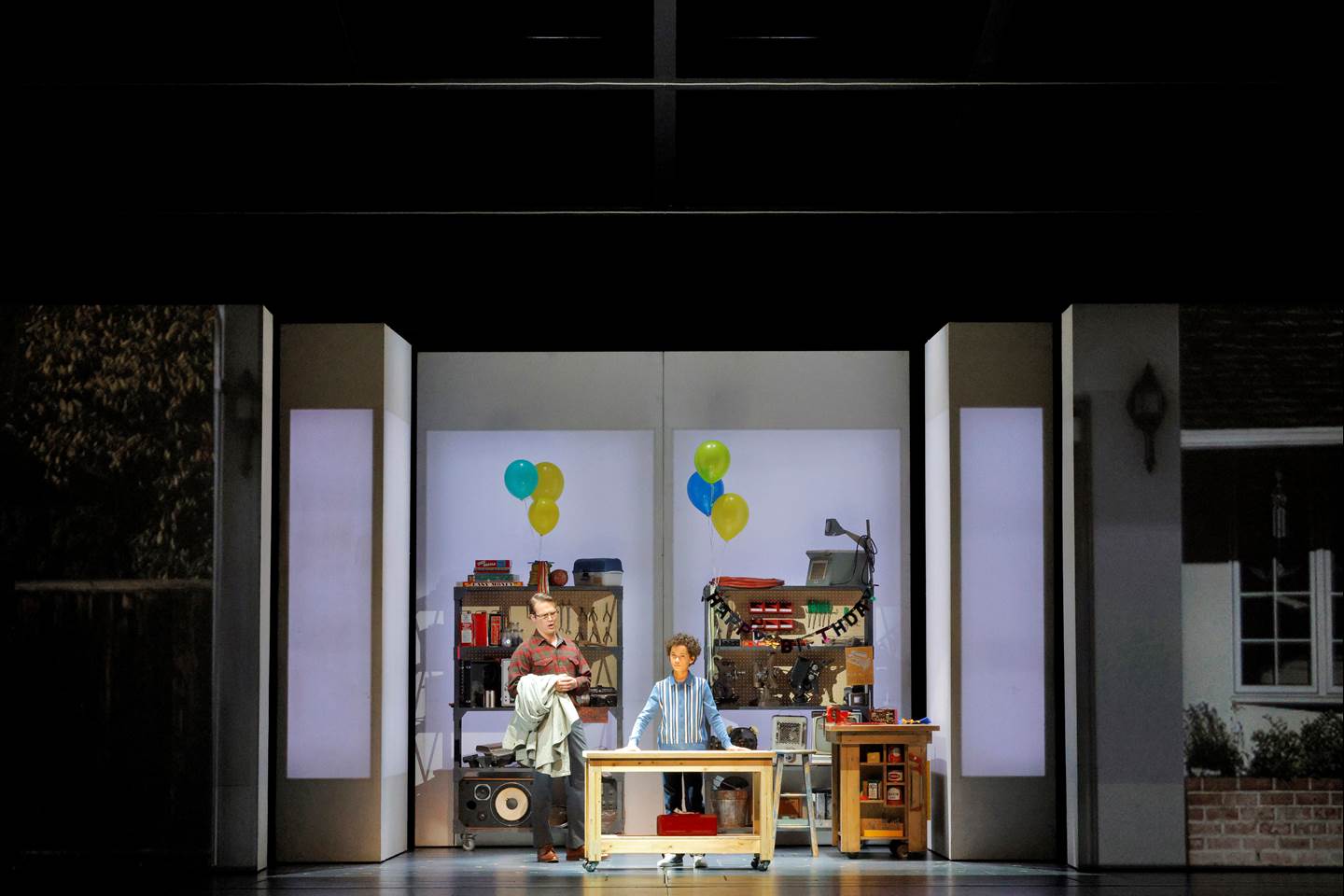 man and child on stage with a set that looks like a garage