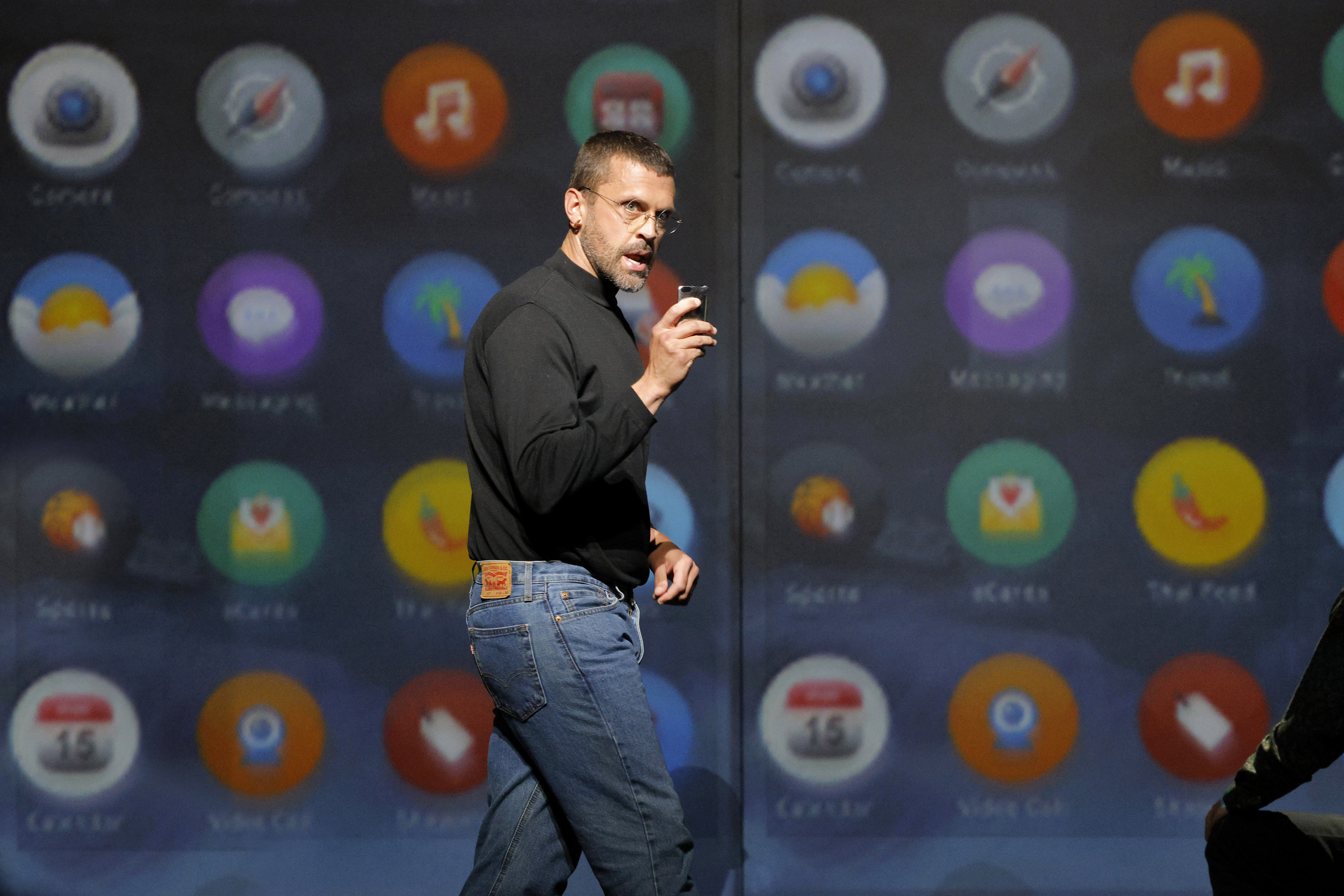 man showing off phone on stage