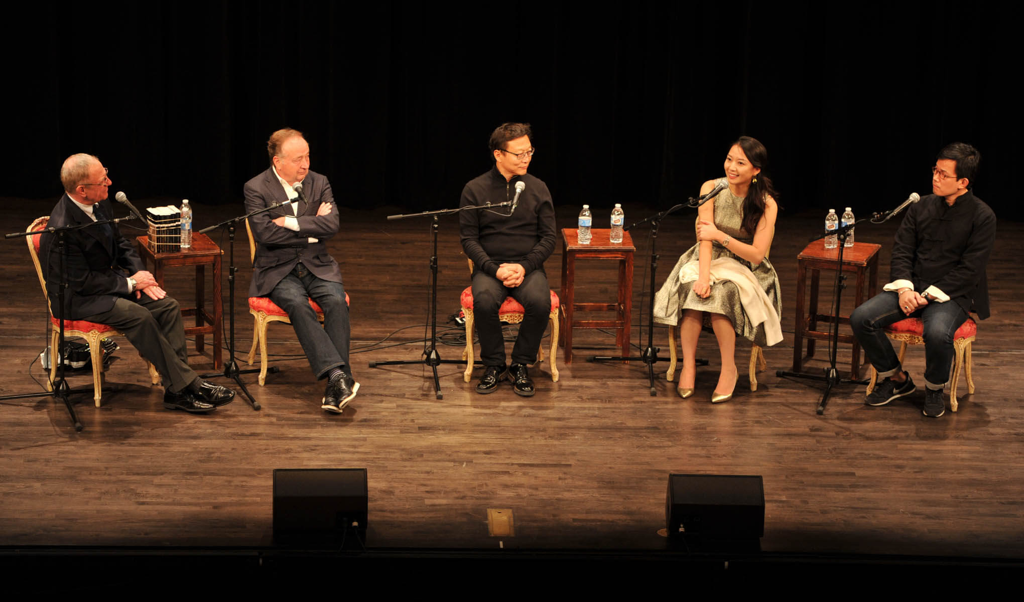 5 people sitting around having a discussion on a stage.