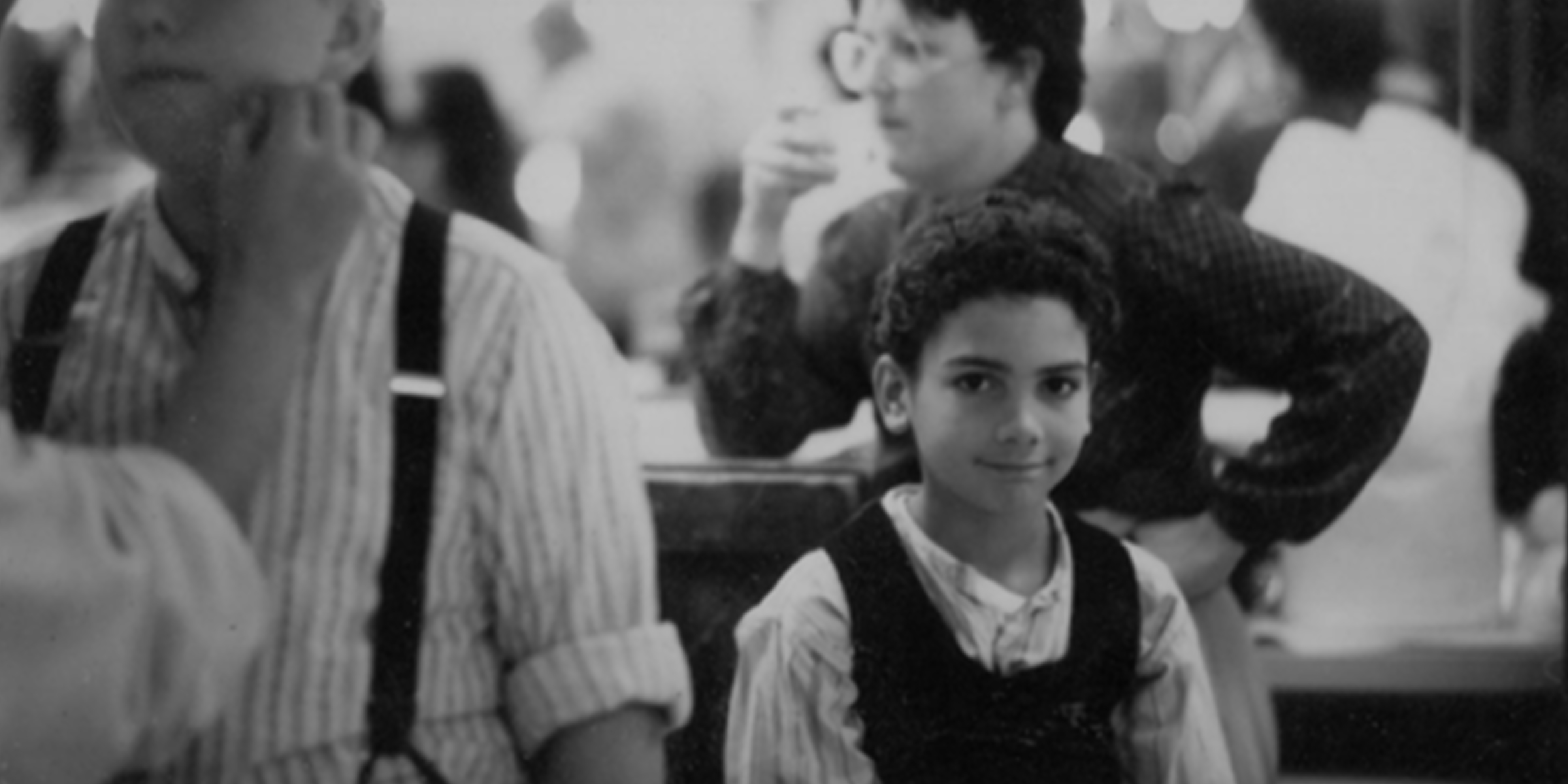 Black and white photo of child smiling at camera in a crowded room