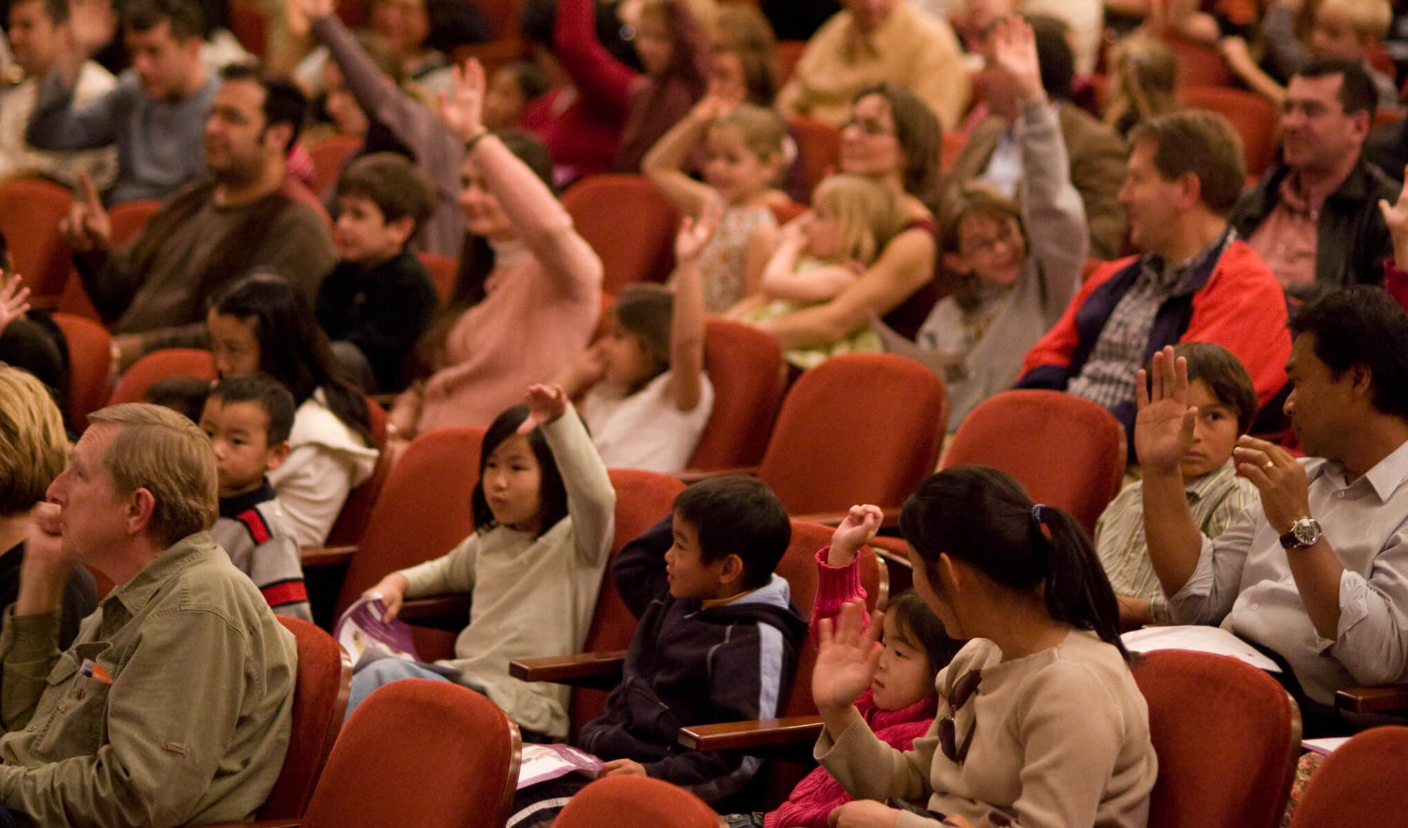 Students in the audience raising their hands. Photo by Kristen Loken