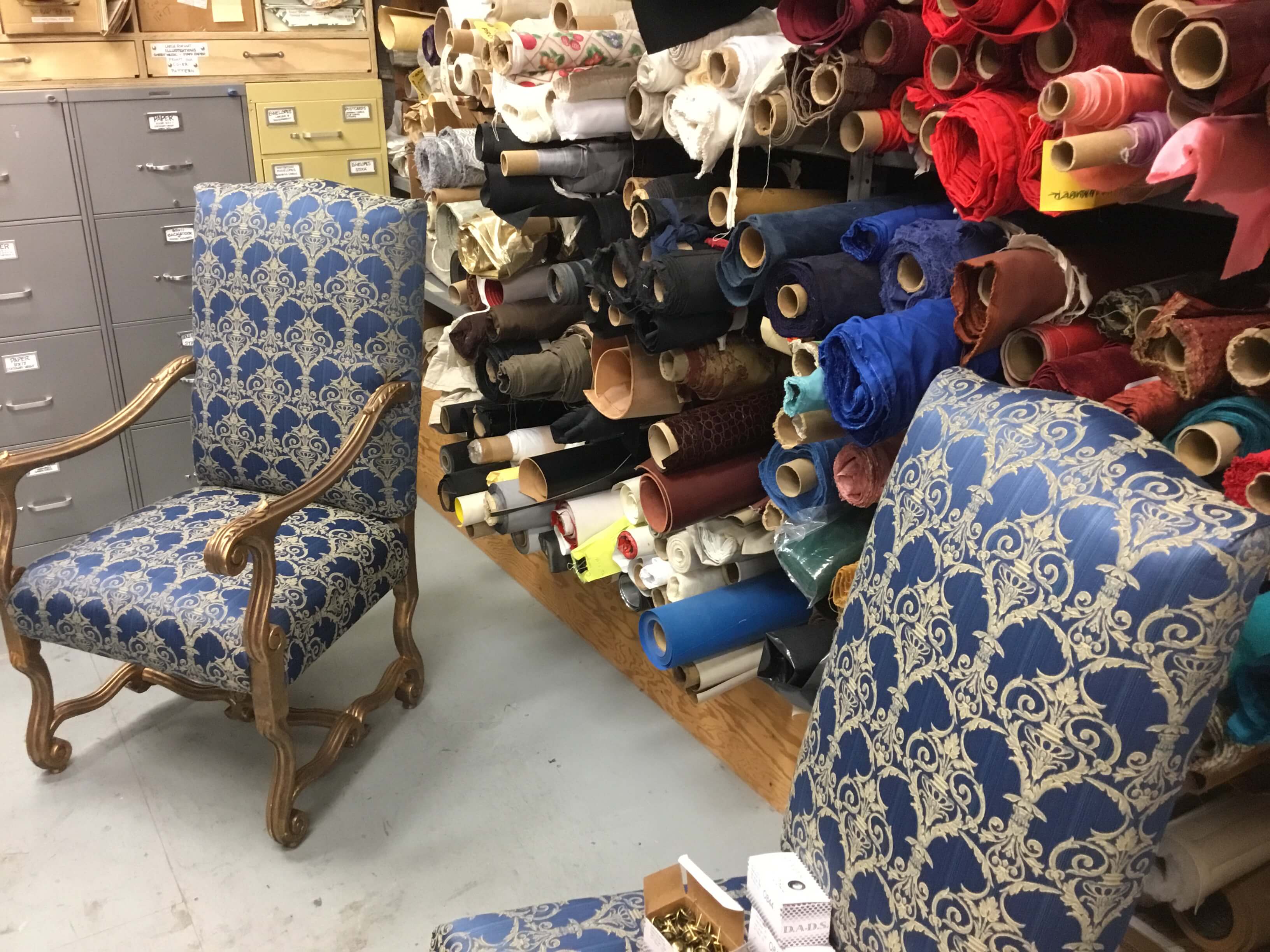 SFO-upholstered chairs in the fabric/upholstery room in the fly tower and Properties Master Lori Harrison testing out the upholstery nails.