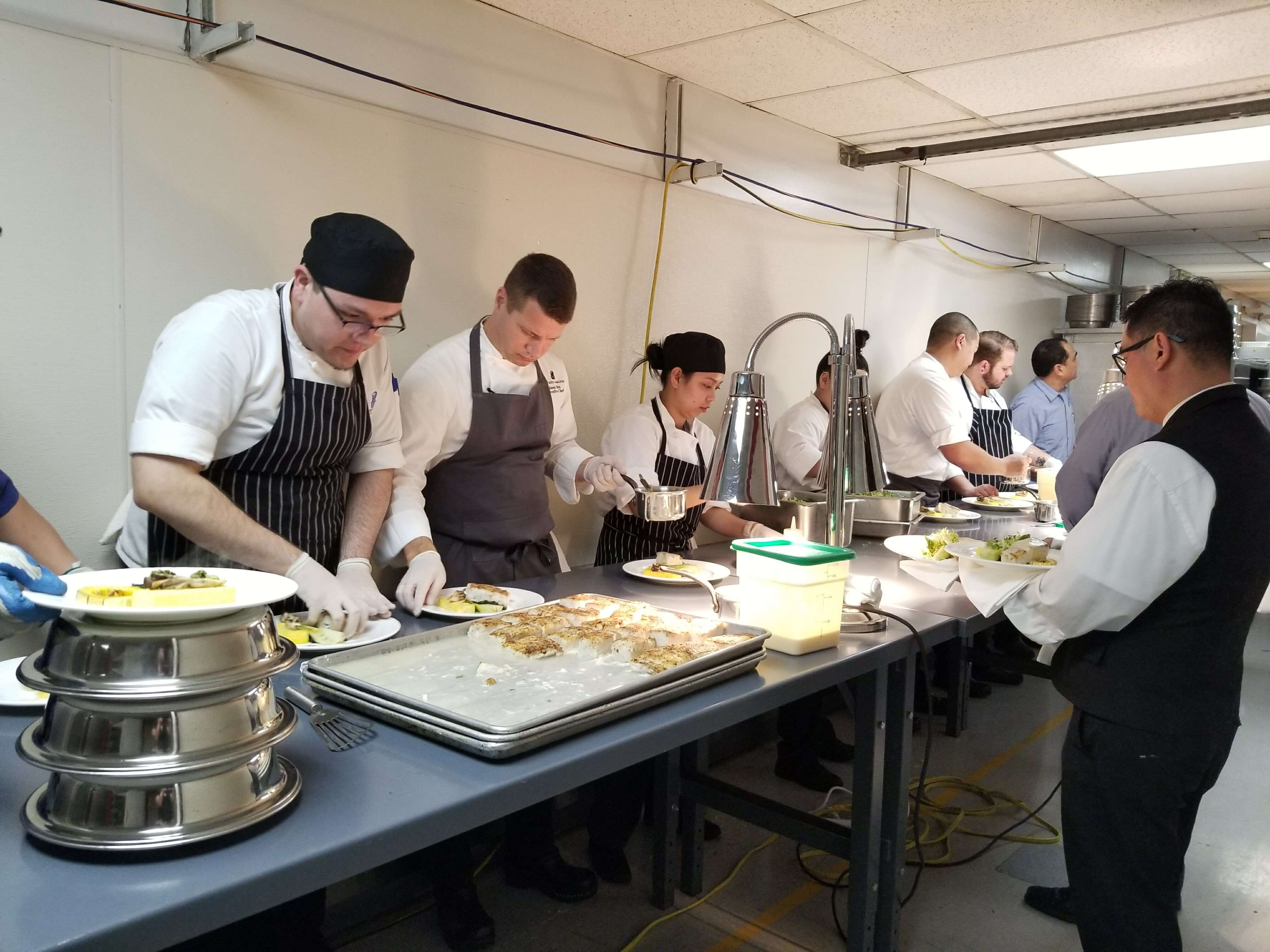 An expanded staff at the Ritz finishes the entr&eacute;es before they are whisked into the ballroom.