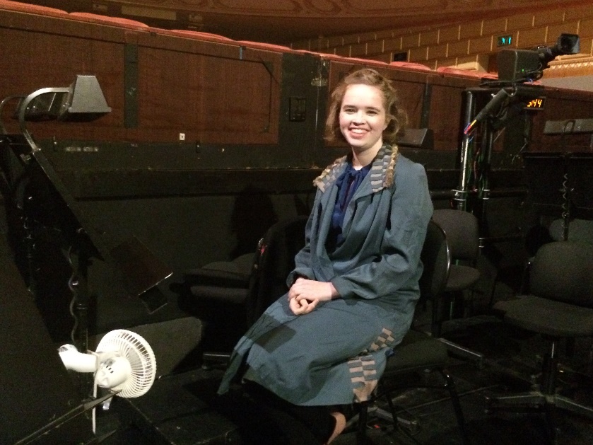 Violin student Lucy Nelligan sitting in the Concertmaster&rsquo;s chair in the Opera House pit.